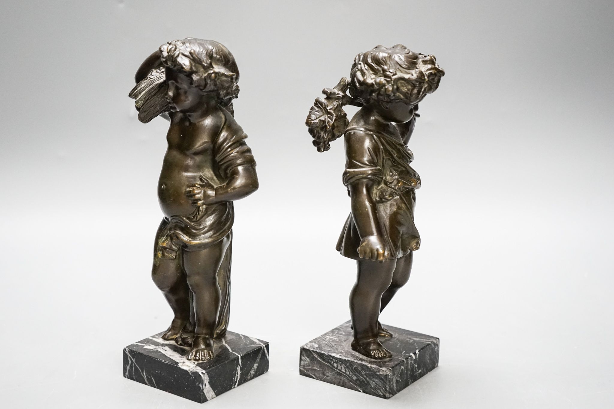 A pair of Victorian bronze putti emblematic of Summer and Autumn, on marble bases 22cm